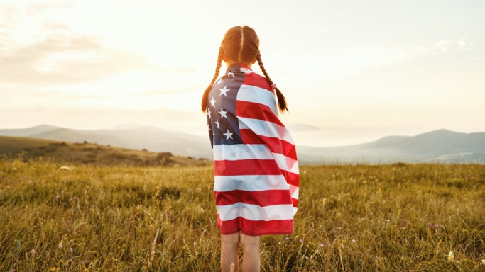 happy child girl with flag of united states enjoying the sunset on nature america 4th of july independence day