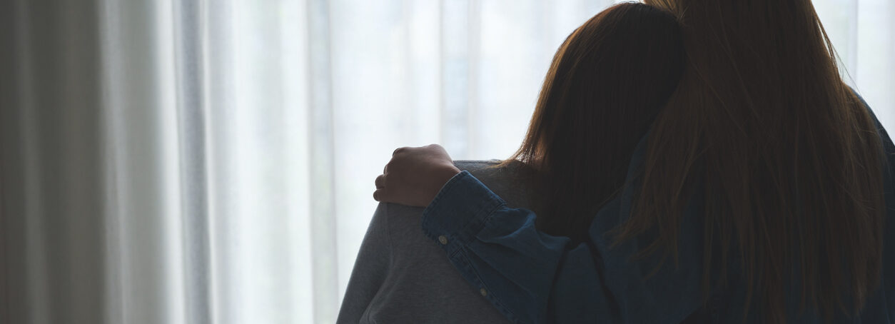 Silhouette image of a woman hugging her friend to comforting and giving encouragement in bedroom