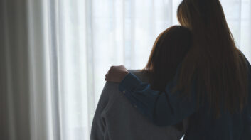 Silhouette image of a woman hugging her friend to comforting and giving encouragement in bedroom